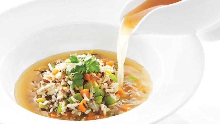 Vegetable soup being poured into a bowl