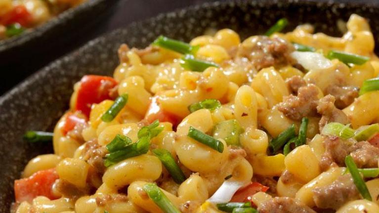 Bowl of macaroni and cheese with hamburger and garnishes