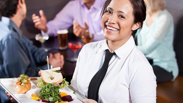 Female server carrying tray with food