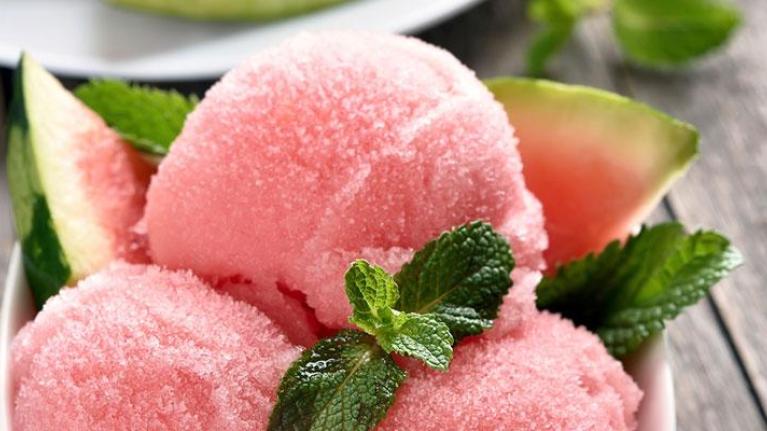 Bowl of watermelon sorbet with mint served on outdoor wooden surface