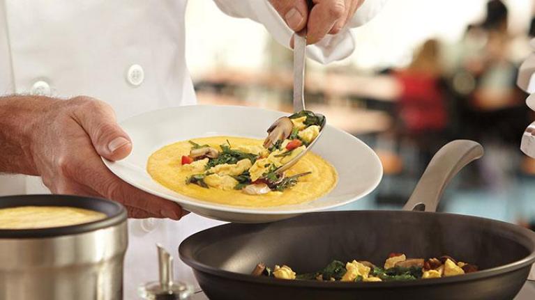 Cook serving up a dish of catered food