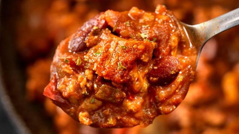 Spoon over bowl of steak chili with kidney beans