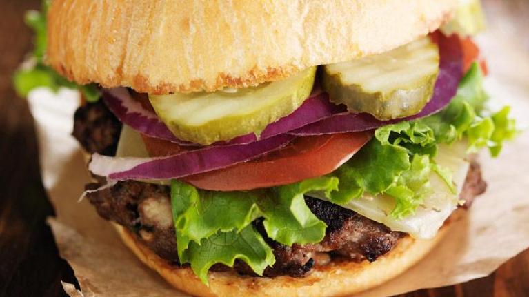 Gourmet hamburger on wax paper and wooden surface