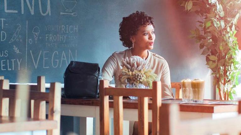 Two women sitting at a table chatting over tall lattes