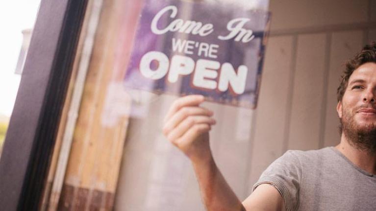 Man turning over open sign in shop window