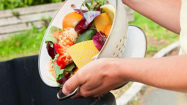 Person dumping food waste into trash can