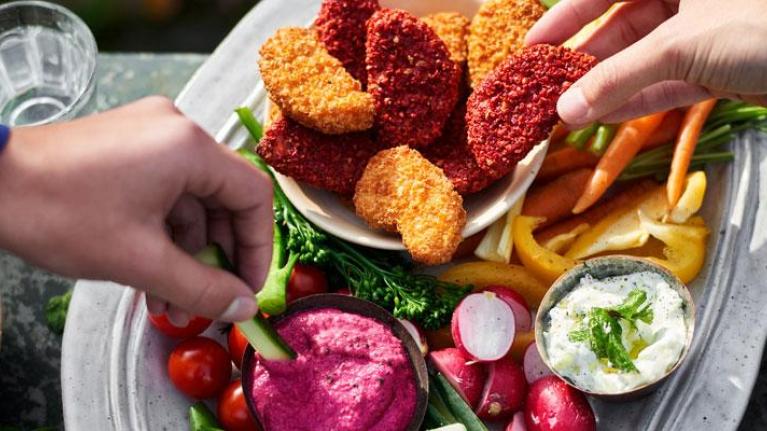 Two people sharing a healthy snack of vegetable dips