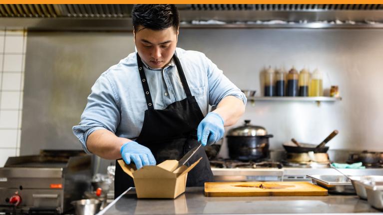 Chef adding food to to-go container