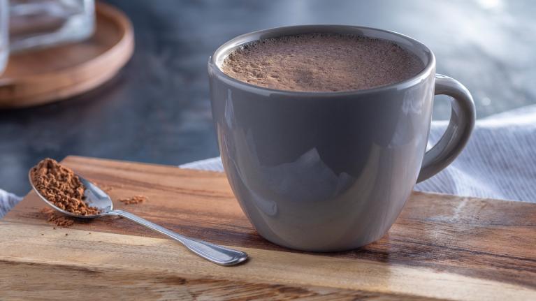 Hot cocoa in a cup with cocoa on spoon