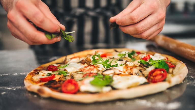 Pizza toppings being added by chef