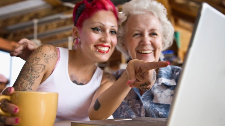 Two women drinking coffee viewing computer screen