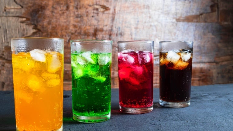 4 beverages shown at a diagonal - one yellow, one green, one red and one that looks like black cola