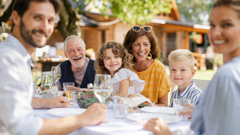 Three generations eating together at an outdoor dinner table