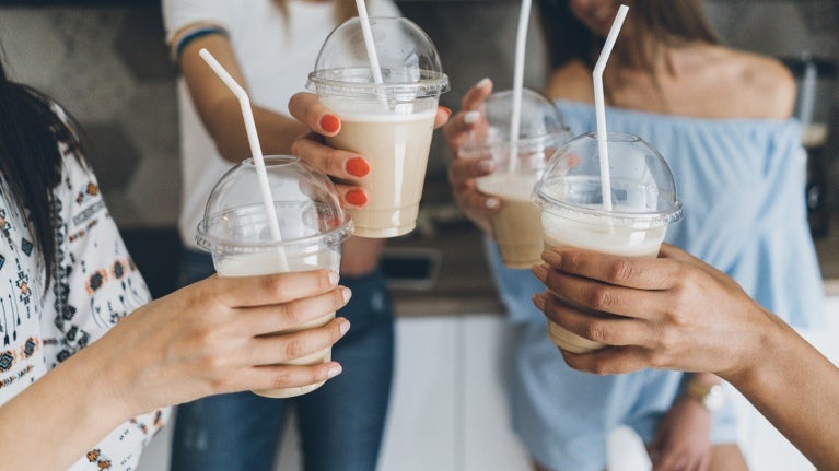 people holding iced coffee with straws