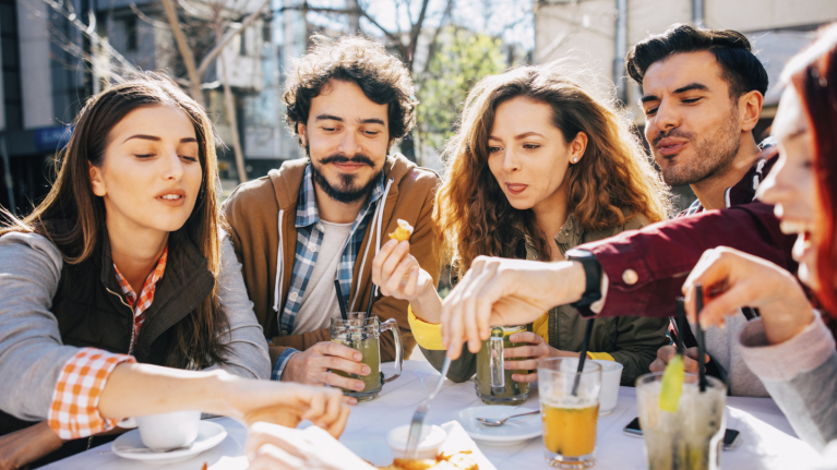 Group of friends eating at table outside