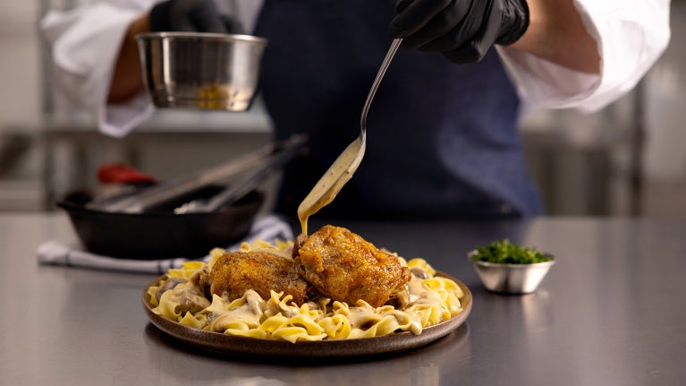chef adding sauce to plated meal