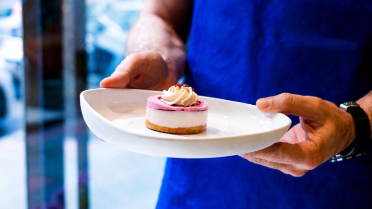 Customer holding a mini cheesecake dessert 