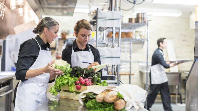 Two female chefs in a professional kitchen with fresh food on the table
