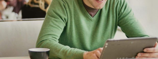 man in a green sweater, typing on his computer