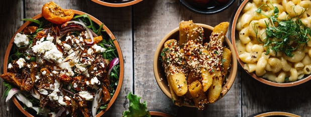 Assortment of prepared dishes, including pasta, vegetables, and entrées, served family-style.