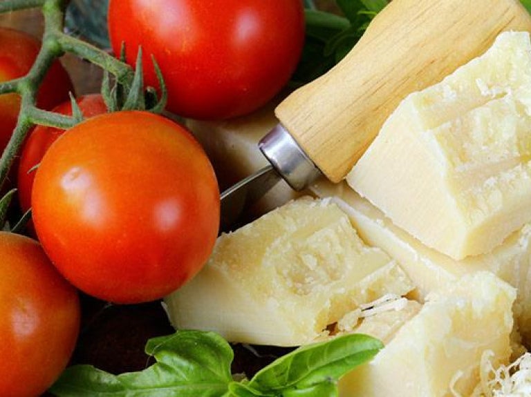 Fresh parmesan cheese with tomatoes and basil on wooden board