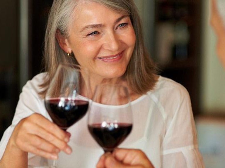 Two baby boomers at a restaurant drinking a glass of red wine
