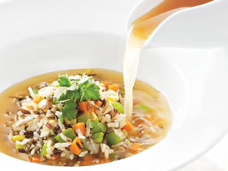 Vegetable soup being poured into a bowl