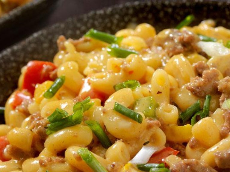 Bowl of macaroni and cheese with hamburger and garnishes