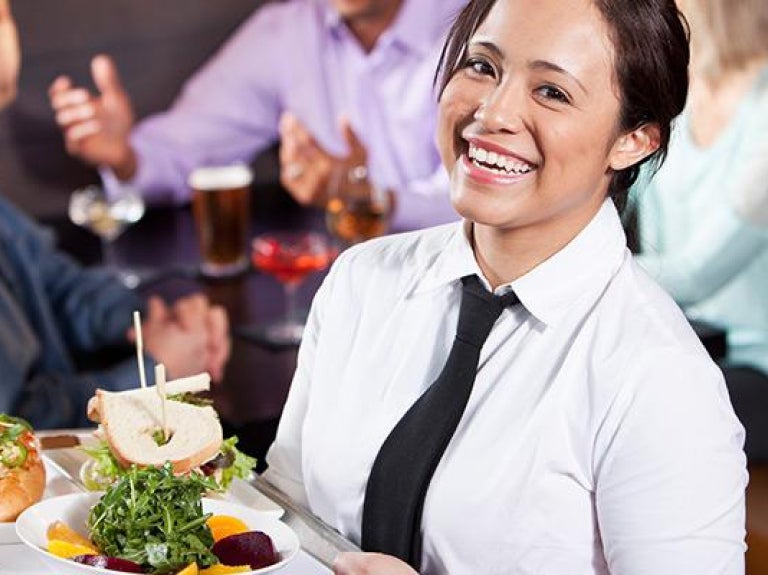 Female server carrying tray with food