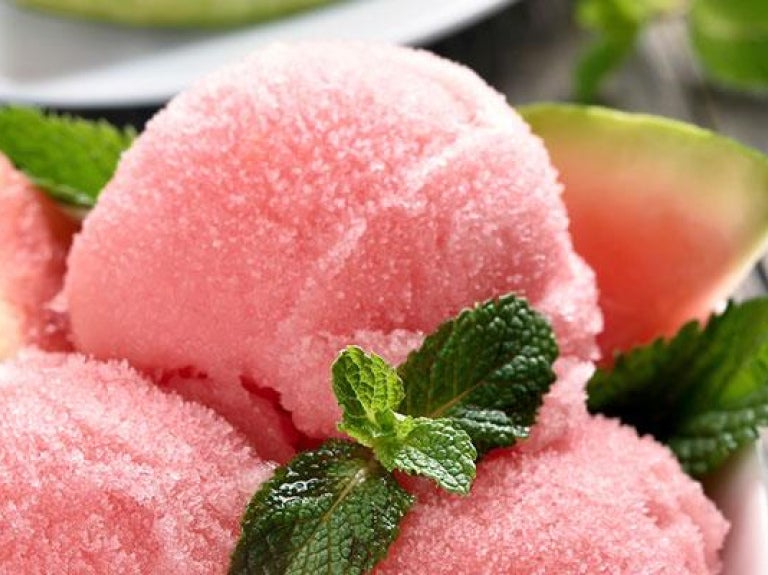 Bowl of watermelon sorbet with mint served on outdoor wooden surface