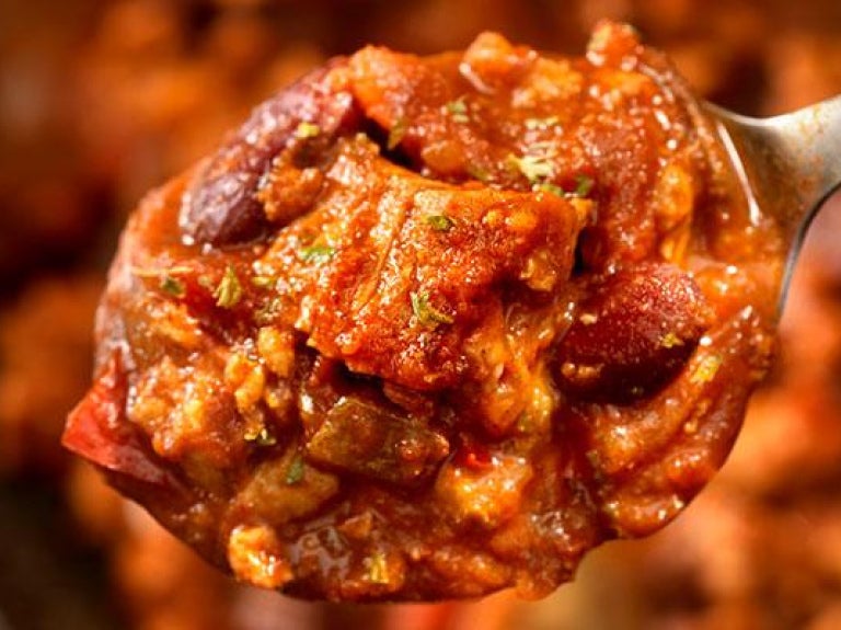 Spoon over bowl of steak chili with kidney beans