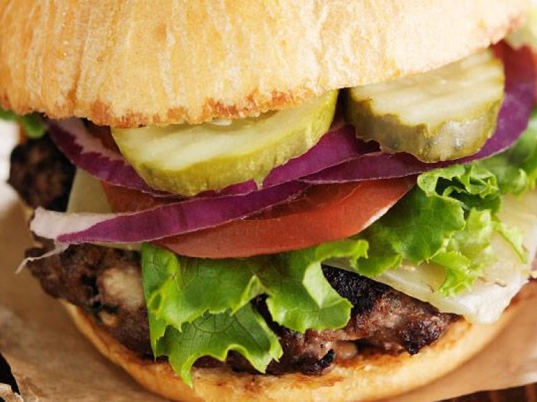 Gourmet hamburger on wax paper and wooden surface
