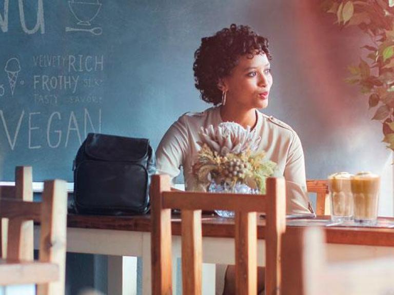 Two women sitting at a table chatting over tall lattes