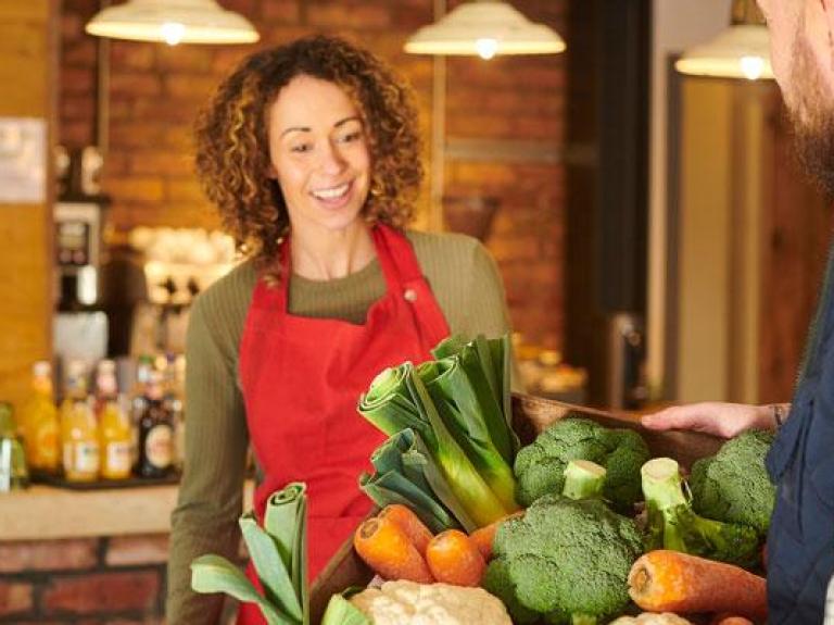 Farmer delivering a basket of local produce to a foodservice cafe owner