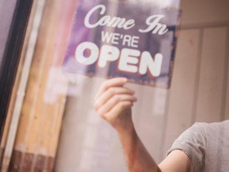Man turning over open sign in shop window