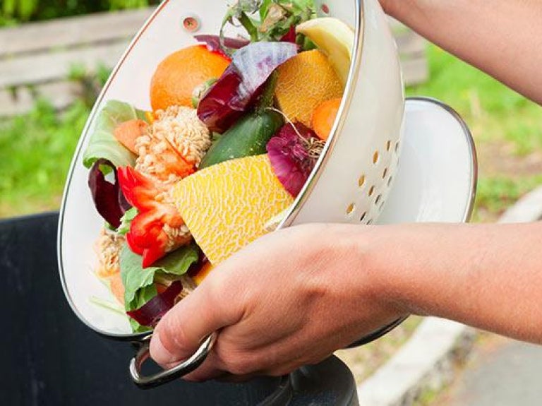 Person dumping food waste into trash can