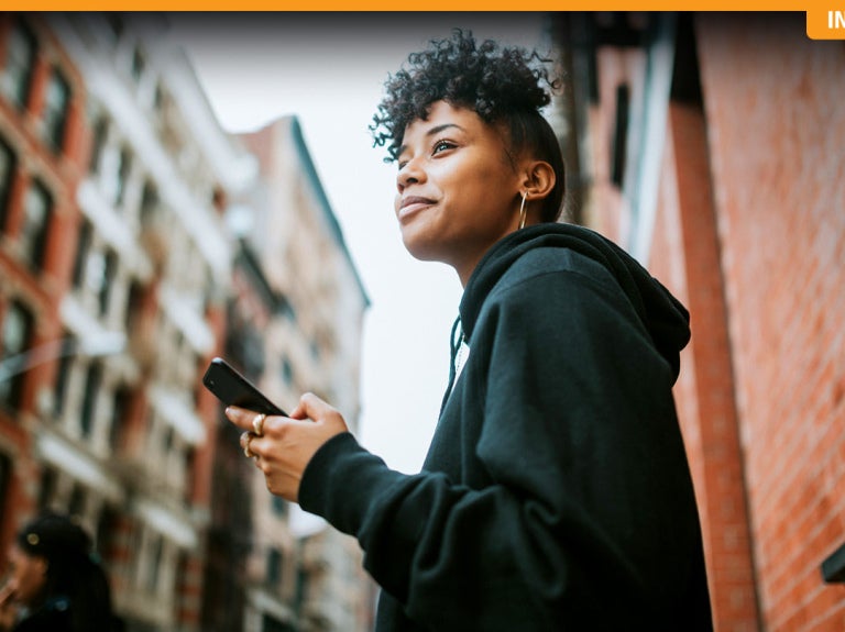 Woman holding cell phone in street