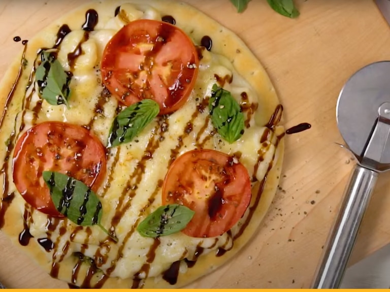 Stouffer's White Cheddar Macaroni and Cheese on a pizza with tomatoes