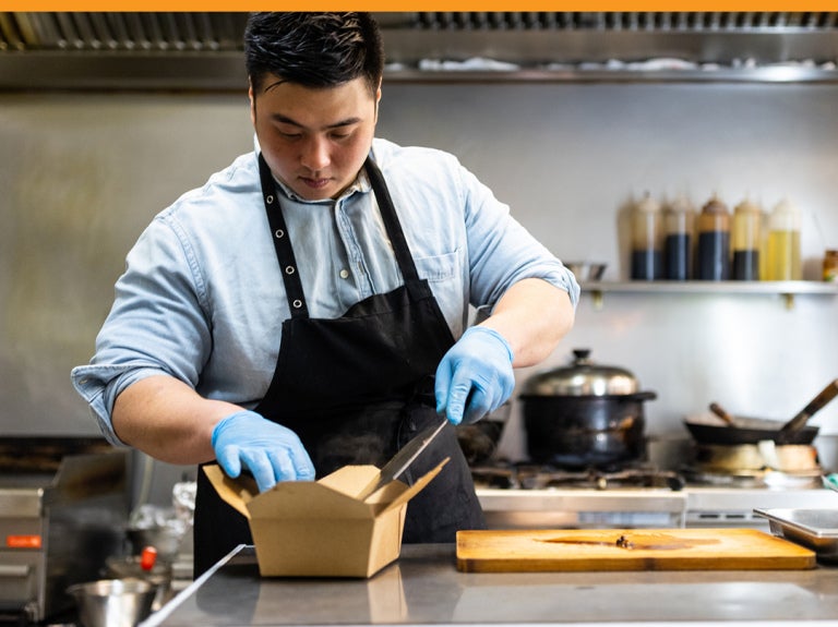 Chef adding food to to-go container