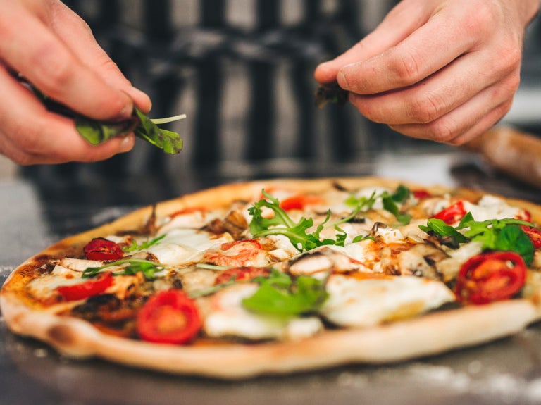 Pizza toppings being added by chef