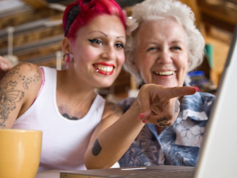 Two women drinking coffee viewing computer screen