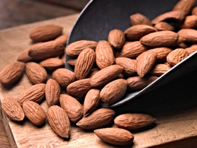 Scoop of nuts on wooden board