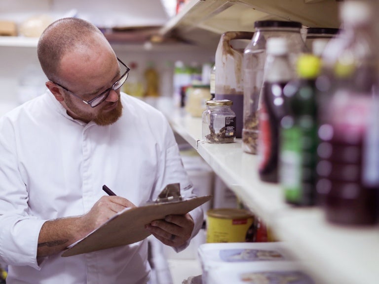 chef taking inventory of stock with clipboard and pen