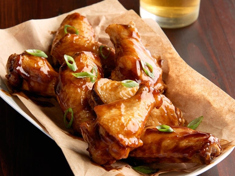 glazed chicken wings in basket on table