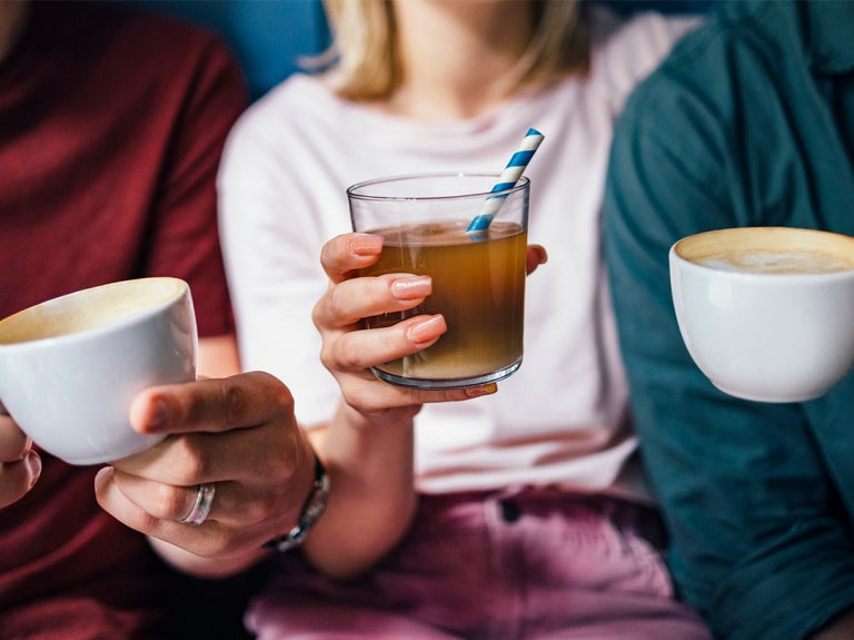 men and a woman holding hot and iced coffee in a cup and mug