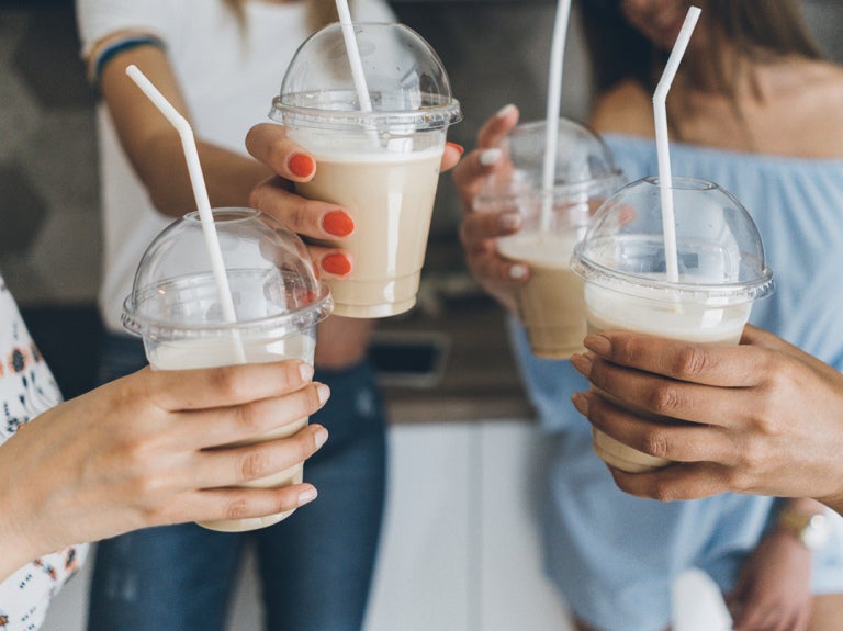 people holding iced coffee with straws