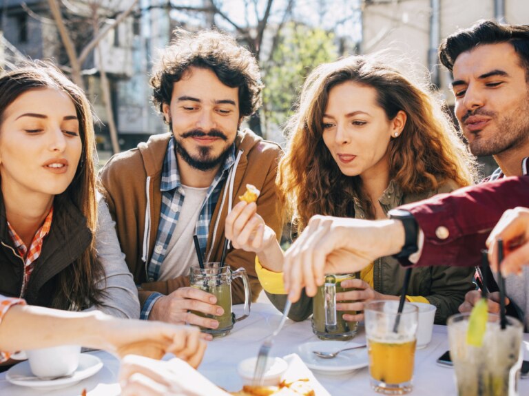 Group of friends eating at table outside
