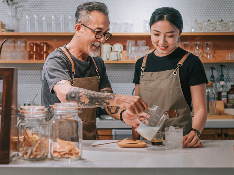 man and woman behind a counter pouring drinks