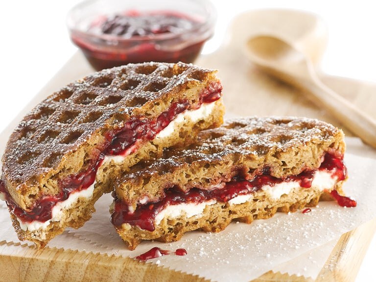 cut sandwich on wooden board with bowl of jam and wooden spoon