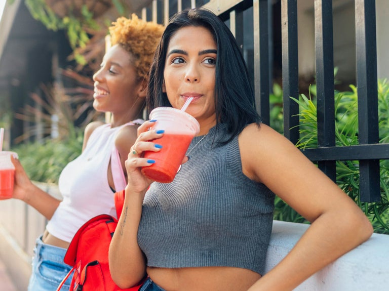 two women standing outside with a fruit beverage in their hands